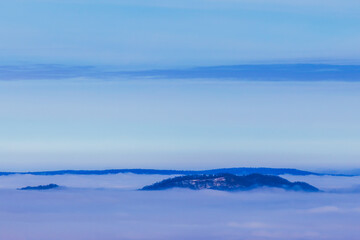 The tops of the hills rise above the clouds