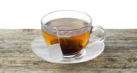 Tea bag in glass cup with hot drink on wooden table against white background