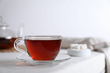 Refreshing black tea in cup on light table. Space for text