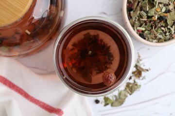 Delicious herbal tea and dry leaves on white table, flat lay