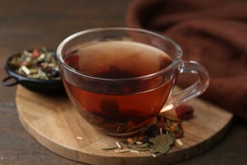 Delicious herbal tea and dry leaves on wooden table, closeup