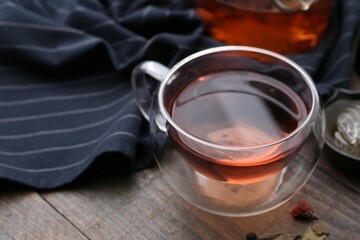 Delicious herbal tea and dry leaves on wooden table, closeup