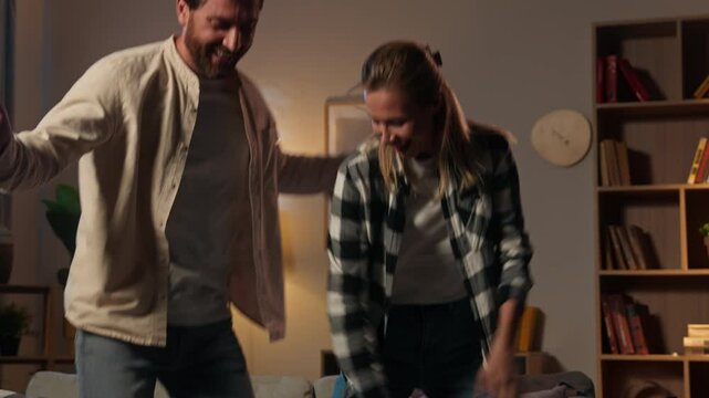 Love couple woman man happy Caucasian family carefree girl guy husband wife tenants jumping at home night party dancing together fun celebrate moving day joy fooling dance music relax domestic weekend
