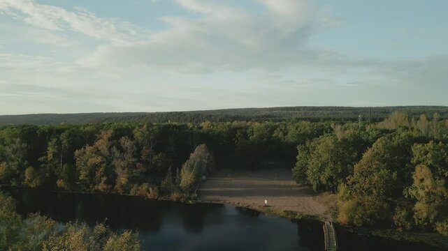 Autumn forest reflecting on calm river at sunset