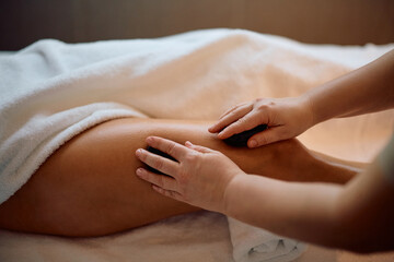 Close up of leg massage with hot stones at spa.