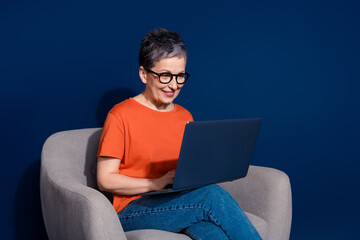Photo portrait of lovely pensioner lady sit armchair netbook dressed stylish orange garment...