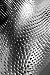 A close up of a shiny, metallic surface with many small dots. The surface appears to be a piece of art, with the dots creating a pattern that is both intricate and visually appealing