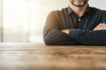 Fototapeta premium A man with his arms crossed is sitting at a table