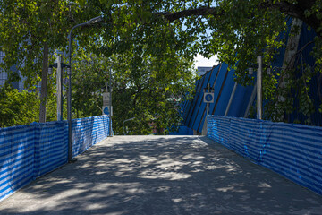 The tranquil path, surrounded by lush green trees and blue building fences