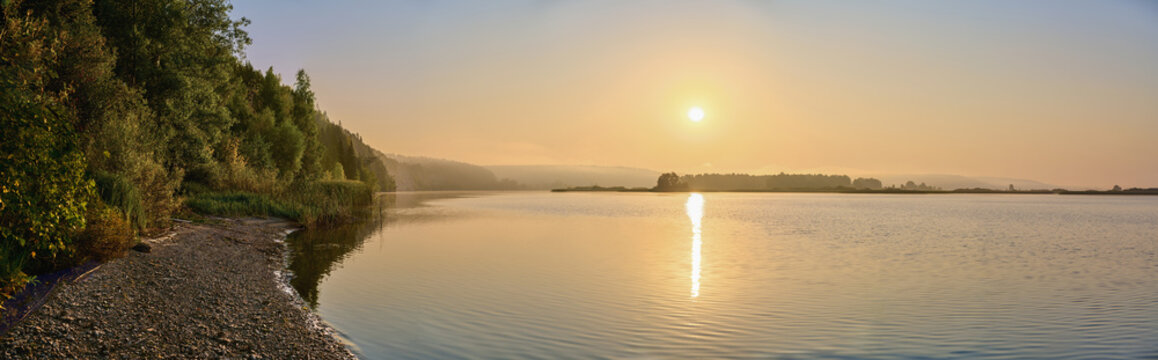 A panoramic view of the morning fog over the river, with the sun shining through.