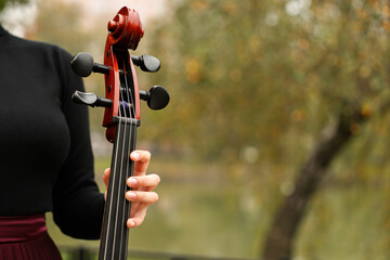 Woman with cello outdoors, closeup. Space for text