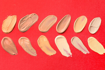 Samples of different foundations on red background, above view