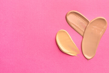 Foundation on pink background, top view with space for text. Smears of cosmetic product