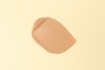 Sample of foundation on beige background, top view