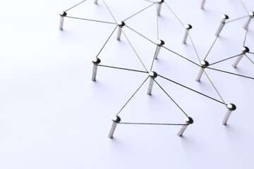 Network connection. Nails linked together by threads on white background, closeup