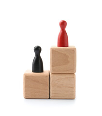 Human figures on wooden blocks, red one on top against white background. Competition concept