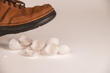 Shoe above broken egg shells,  conceptual image illustrating perception of touchy situation. 