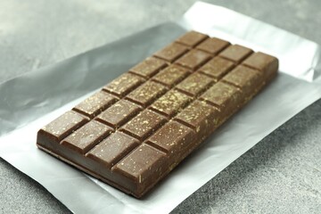 One tasty Dubai chocolate bar with pistachios and knafeh on grey textured table, closeup