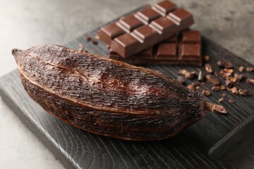 Cocoa pod and chocolate on grey table, closeup