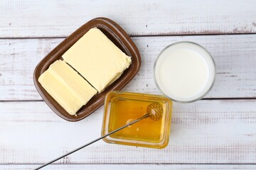 Sweet honey, butter and milk on white wooden table, flat lay