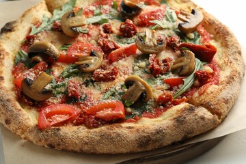 Tasty pizza with mushrooms, tomatoes and arugula on white table, closeup
