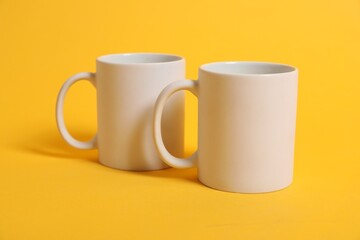 Two blank mugs for branding on orange background. Mockup for design