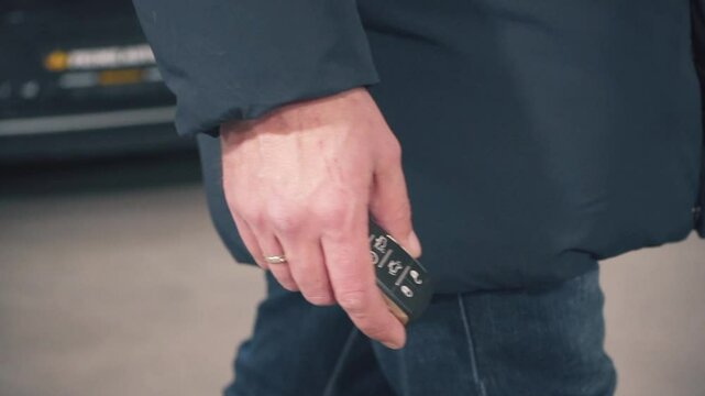 a man hand with car keys goes to the car, close-up