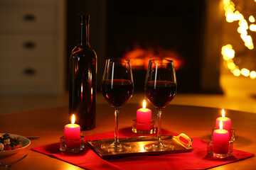 Glasses of red wine and burning candles on table. Romantic dinner