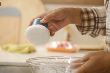 Person Using A Cleaning Brush on A Glass Bowl in A Bright Kitchen