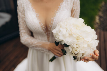 The bride in a white dress holds a bouquet of fresh flowers in her hands. Bride's bouquet.