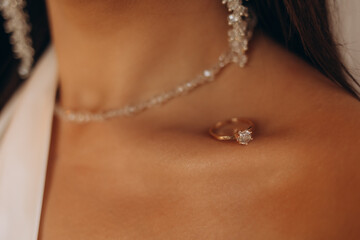 A woman is wearing a necklace and holding it up to her neck. The necklace is a silver chain with a diamond pendant. The woman's hand is holding the necklace