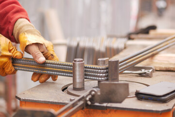 Construction worker bending metal rods at site