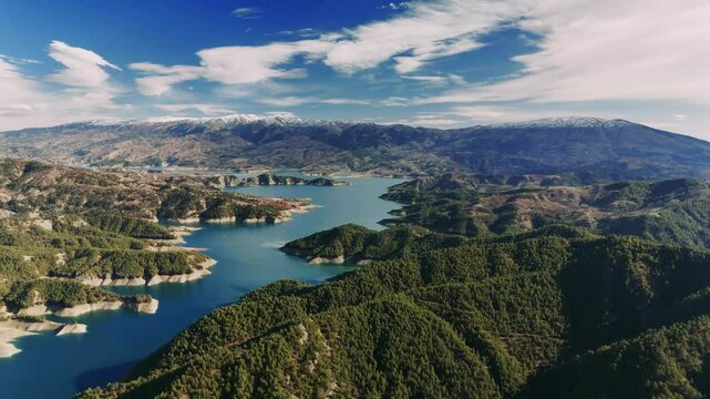 Beautiful taurus mountains surround gokpinar lake in turkey, creating a picturesque landscape with blue water contrasting against green hills and snow-capped peaks under a vibrant sky