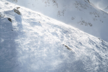 Fototapeta premium Snowdrift with windblown snow creating a dynamic texture under sunlight. A serene and cold winter scene, evoking feelings of adventure, solitude, and nature's raw beauty.