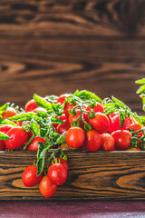 Fresh cherry tomatoes with water drops overflowing a wooden crate