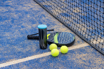 A padel racket and balls resting on a vibrant blue court, ready for an exciting match or practice...