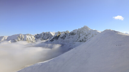 Panorama of the winter peaks of the Tatras from Kasprowy Wierch. A sunny, winter December day. The mountain peaks are covered in thick clouds.
