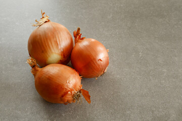 Three onions on a grey countertop