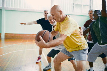 Fototapeta premium Senior men playing basketball in gym with energy and teamwork