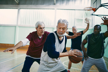 Senior men playing basketball in gym with energy and teamwork