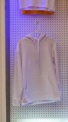 Hoodie blanca de algod&oacute;n en armario industrial con luces RGB, concepto moda, mockup