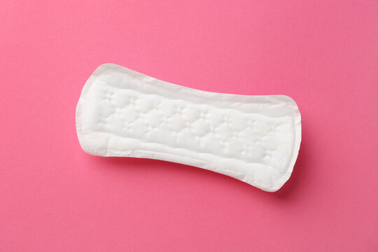 Menstrual pad on pink background, top view