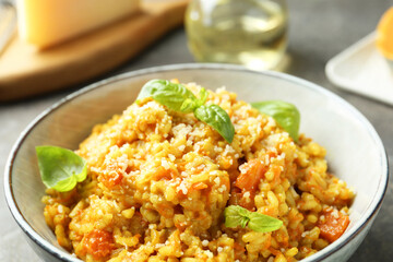 Delicious pumpkin risotto with basil on table, closeup