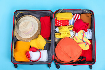 Travel abroad. Packed suitcase on light blue background, top view