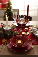 Christmas place setting with festive decor on wooden table in room