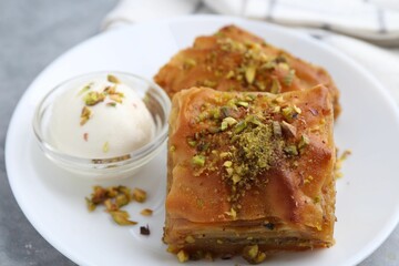 Tasty baklava with chopped nuts and scoop of ice cream on table, closeup
