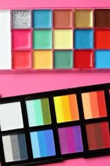Bright face paints on pink background, top view