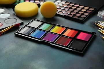 Bright face paints, brushes and sponges on color background, closeup