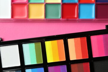 Bright face paints on pink background, top view