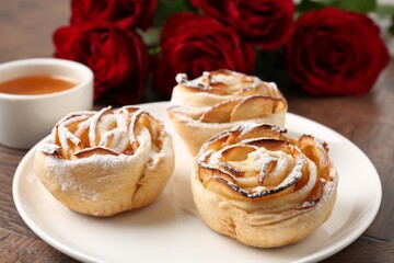 Freshly baked apple roses, honey and beautiful flowers on table, closeup